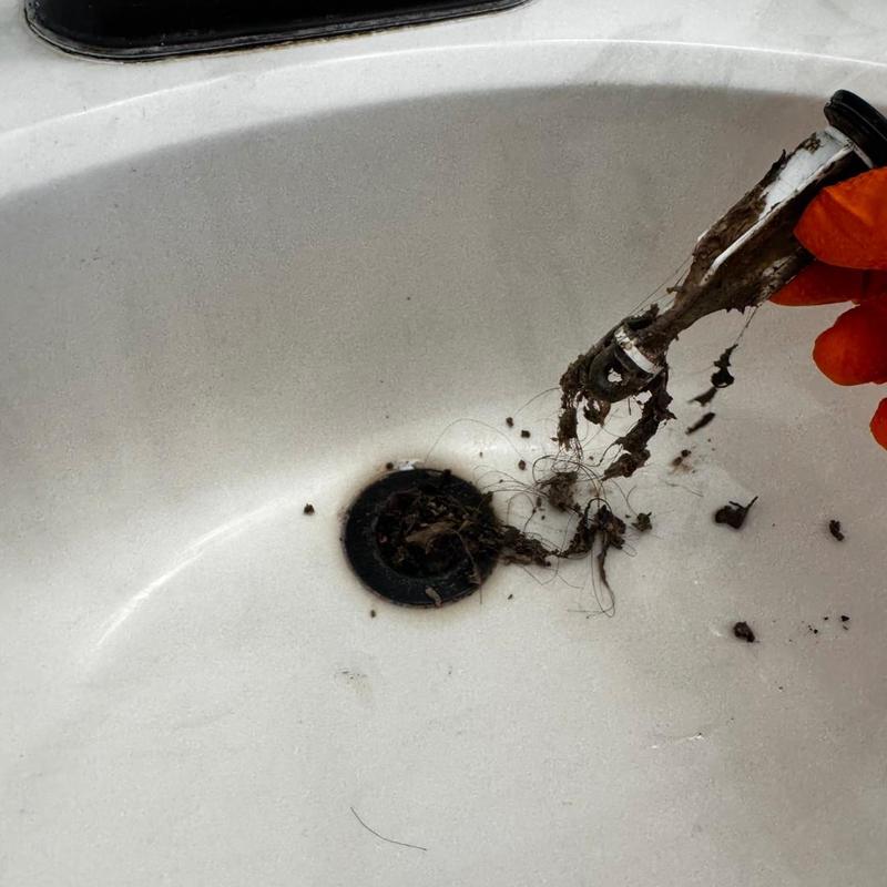 Bathroom drain clog removal with debris on tool
