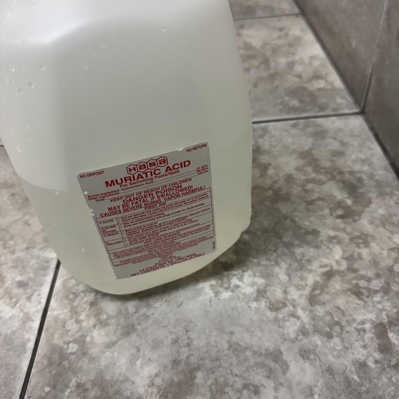 Muriatic acid container for urinal cleaning on tile floor Muriatic acid container for urinal cleaning on tile floor