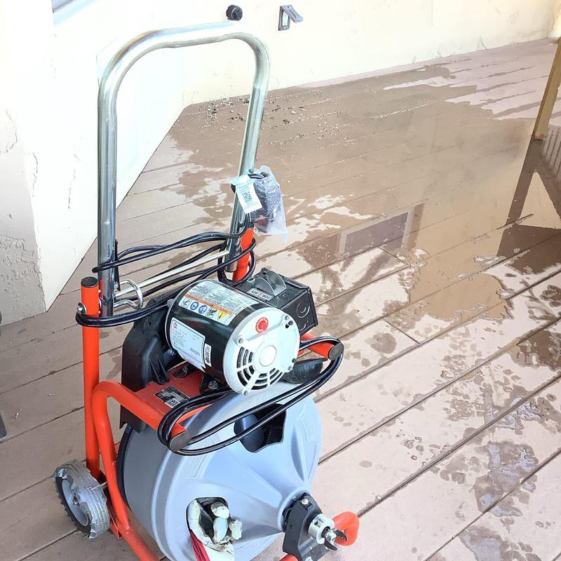 Electric drain snake on deck floor near wall