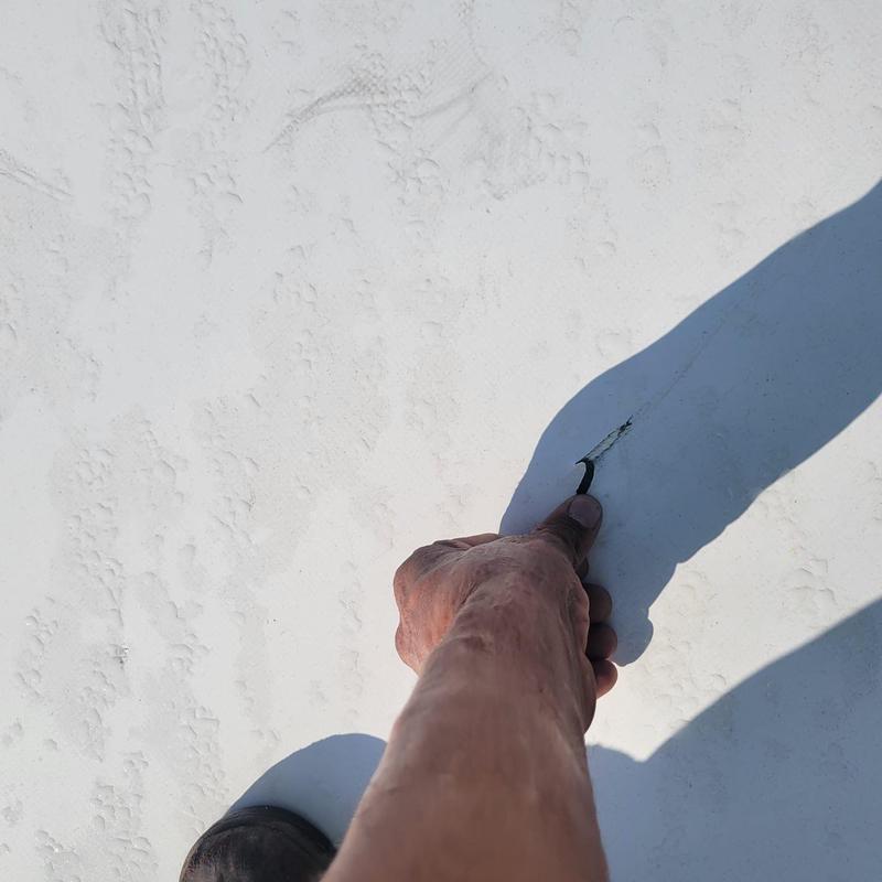 TPO roof membrane tear being inspected by hand