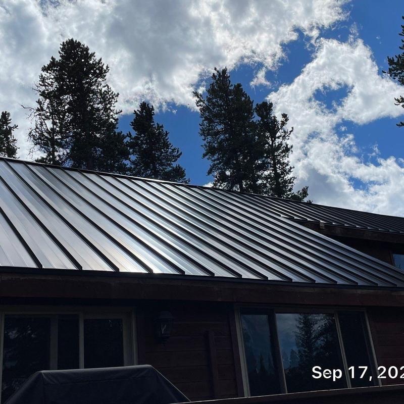 Standing seam metal roof installation with pine trees