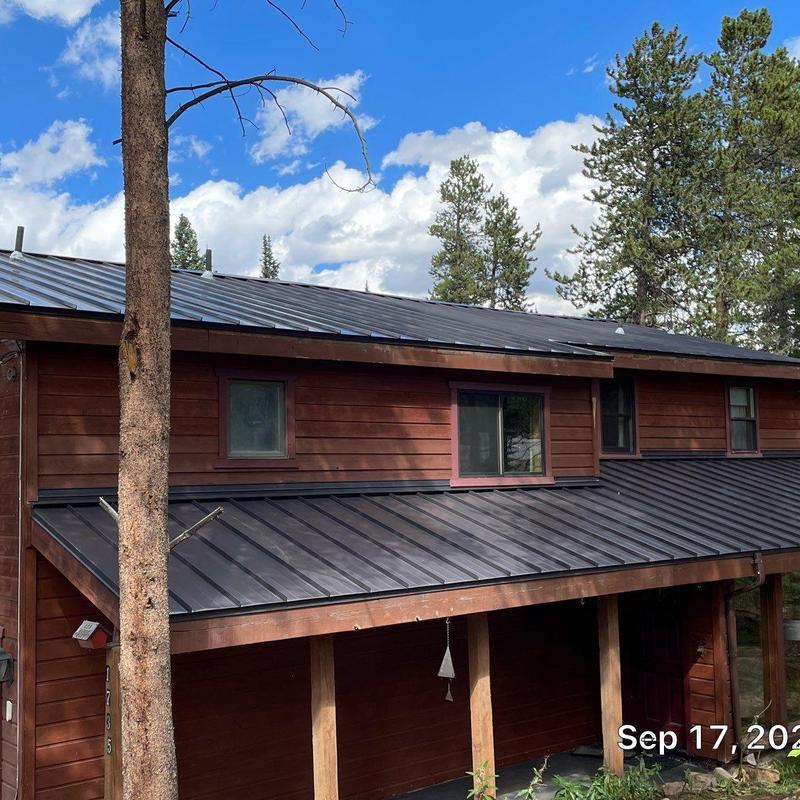 Metal standing seam roof installation on wood cabin