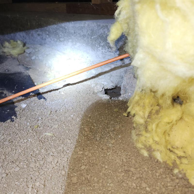 Copper pipe installation with surrounding insulation and dirt floor