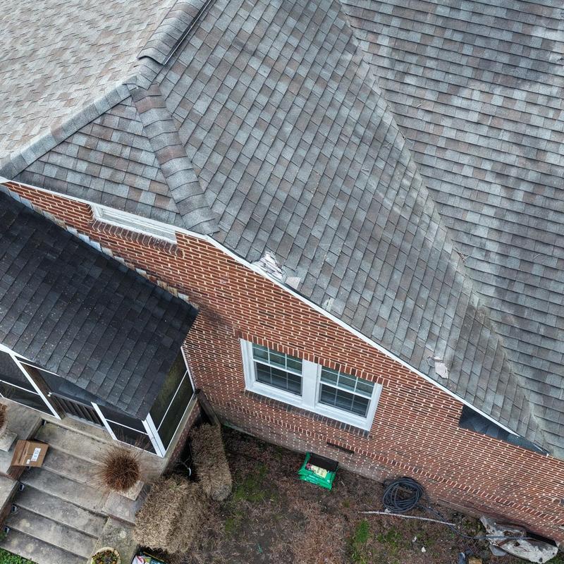 Asphalt shingle roof with damaged tree limb impact