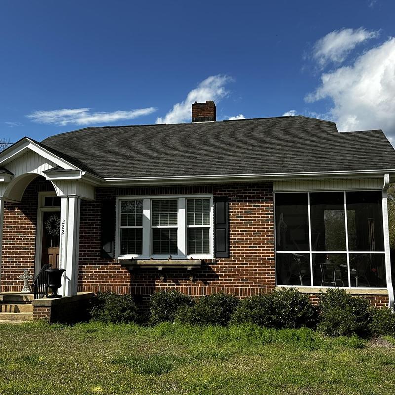 Asphalt shingle roof with tree limb damage on brick home