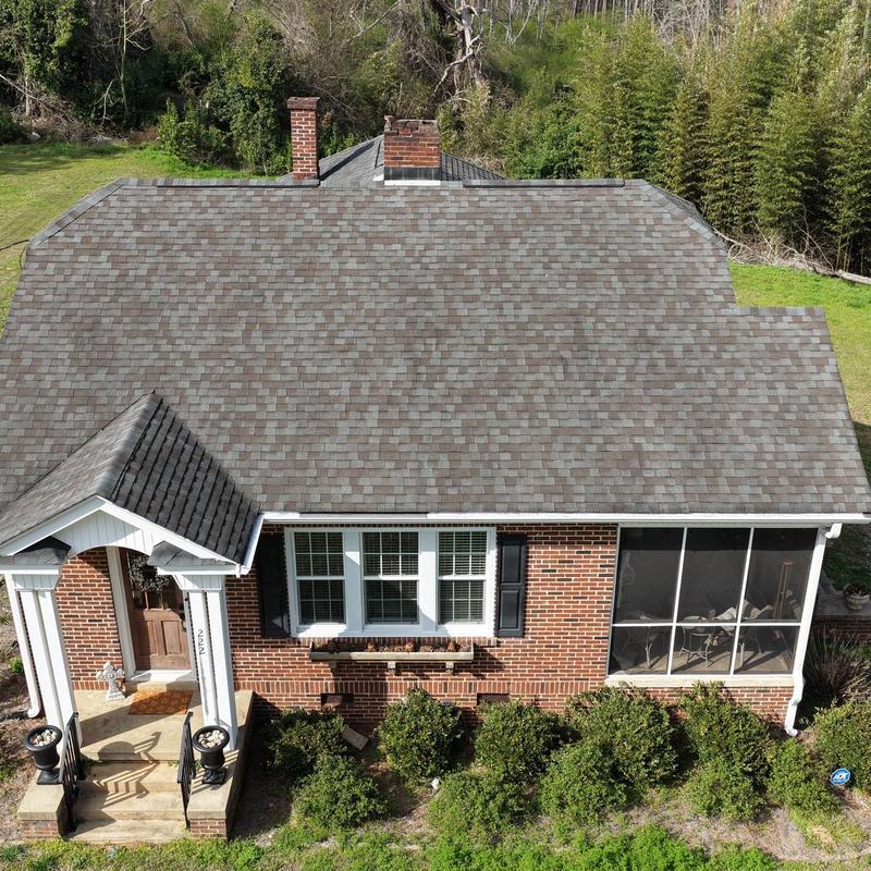 Asphalt shingle roof with tree limb contact on house