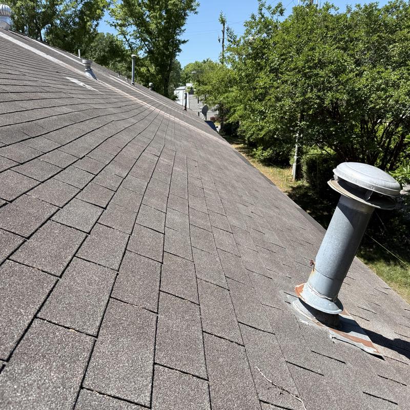 Asphalt shingle roof showing wear and ventilation pipe