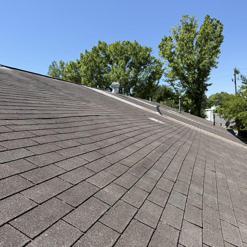 Asphalt shingle roof with wear inspection under clear sky