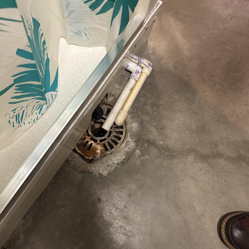 Floor drain with PVC vent pipes near shower stall