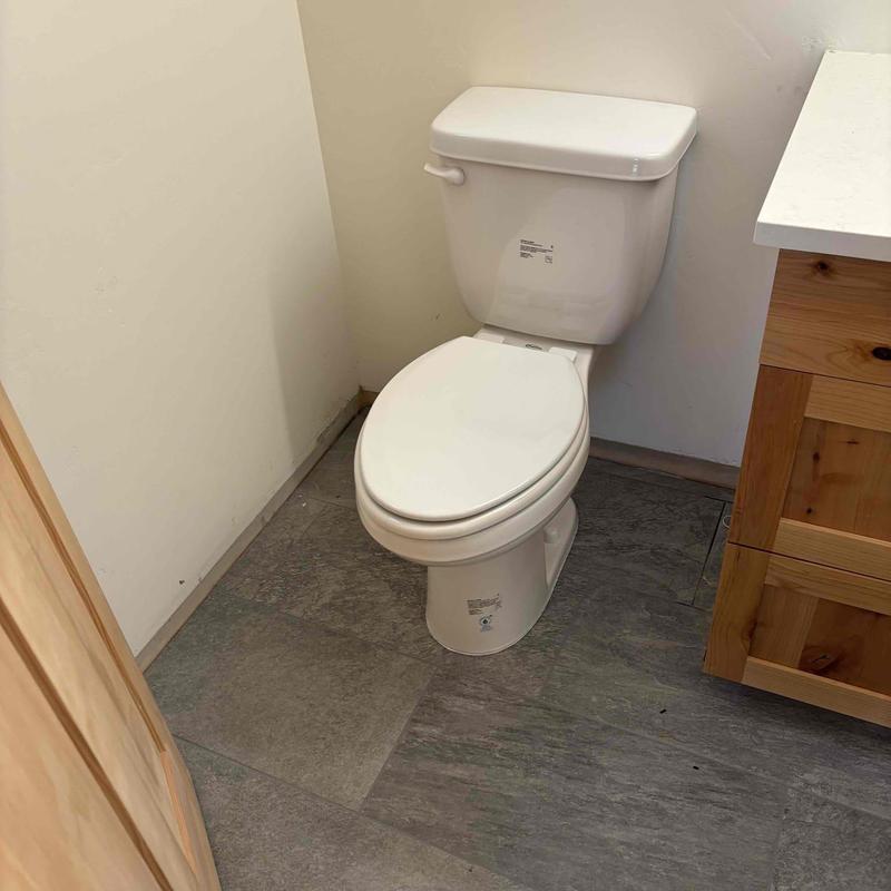 Toilet installation in bathroom corner with wood cabinet