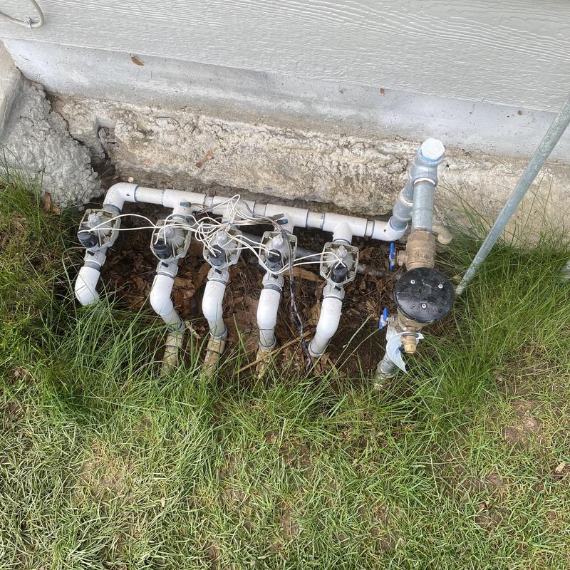 Sprinkler valve manifold with wiring near house foundation