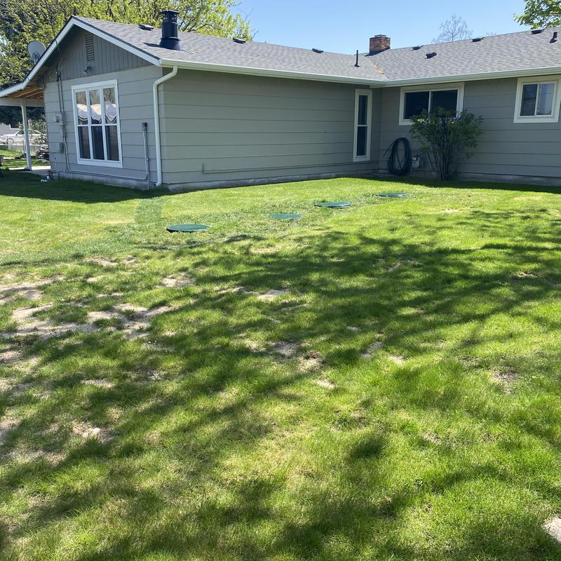 Sprinkler system with septic drain field covers in yard