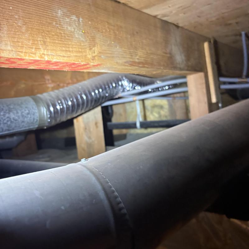 Home plumbing pipes and flexible duct under floor joists