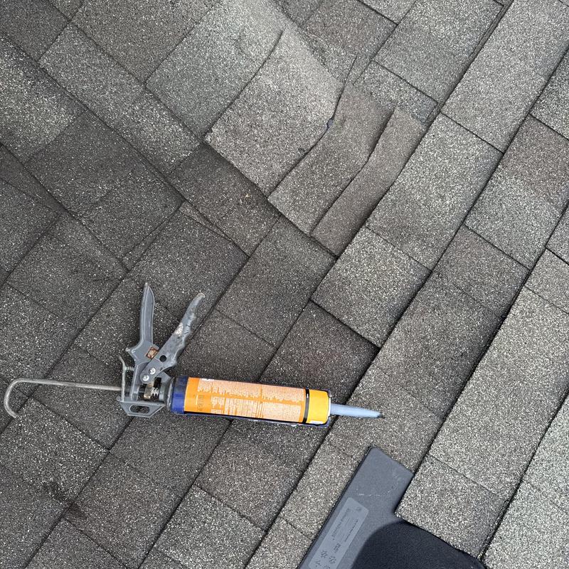 Roof shingles with sealant gun on surface