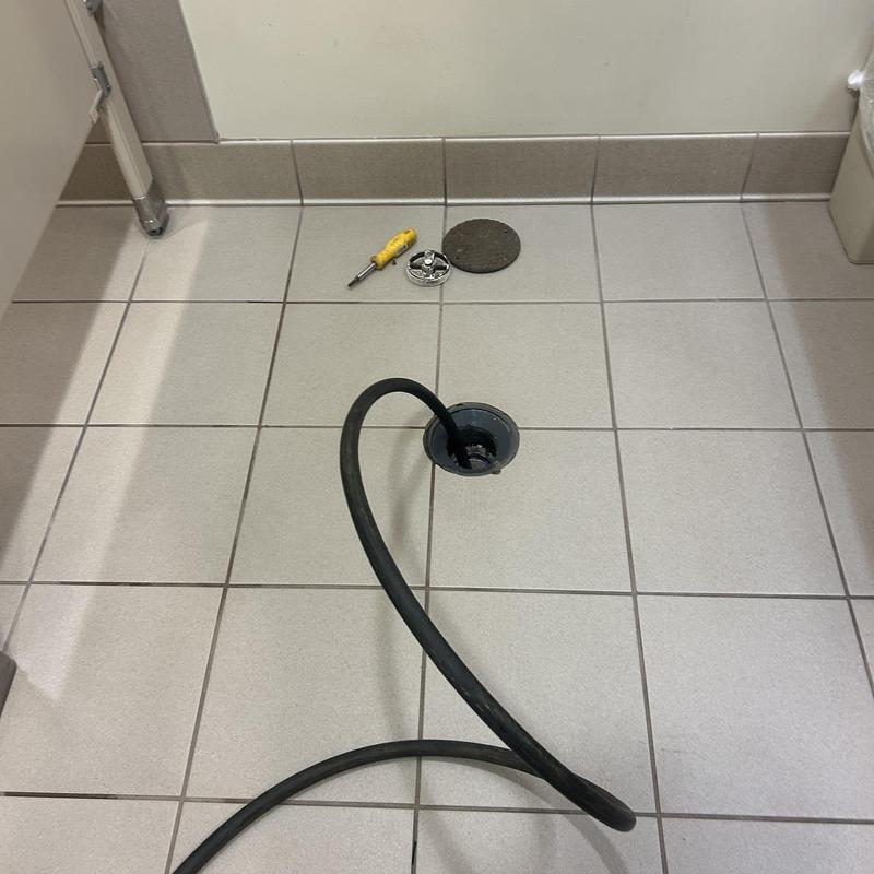 Floor drain hydro-jet cleaning with tools on tile floor