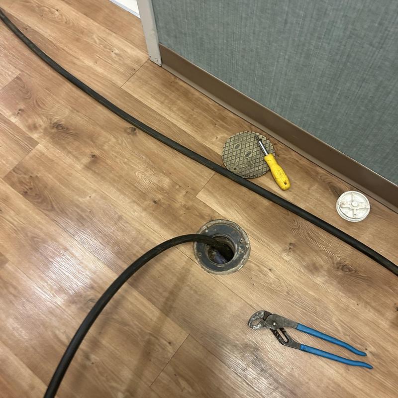 Floor drain hydro-jet cleaning with tools on wood flooring
