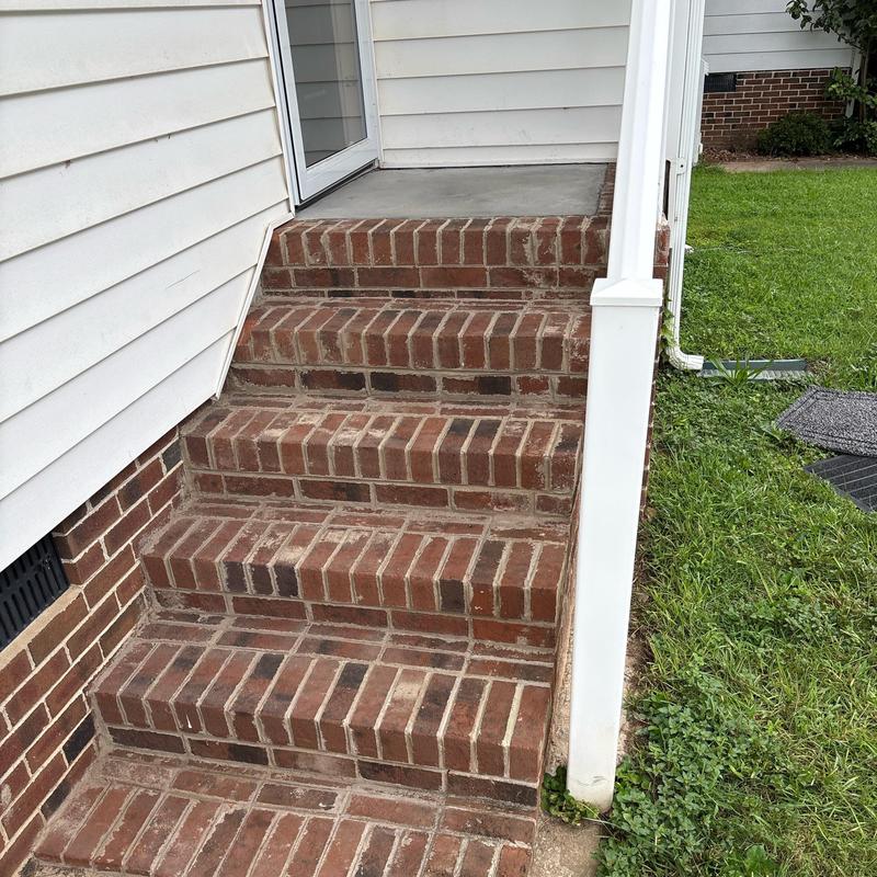 Brick stair steps with concrete landing near house door