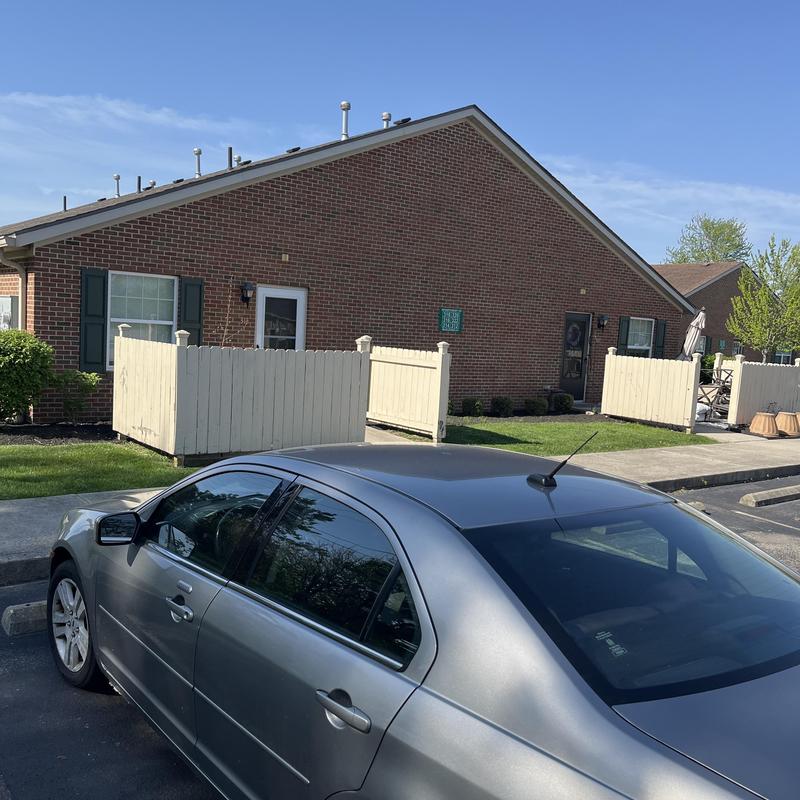Condo brick exterior with roof vents and fencing