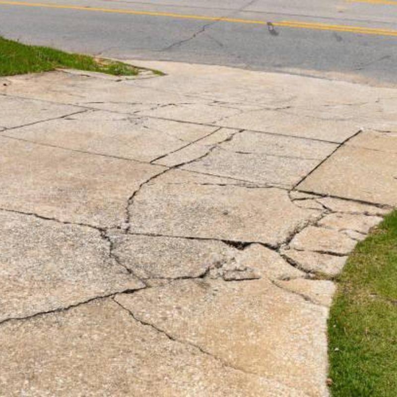 Cracked concrete driveway with visible damage and wear