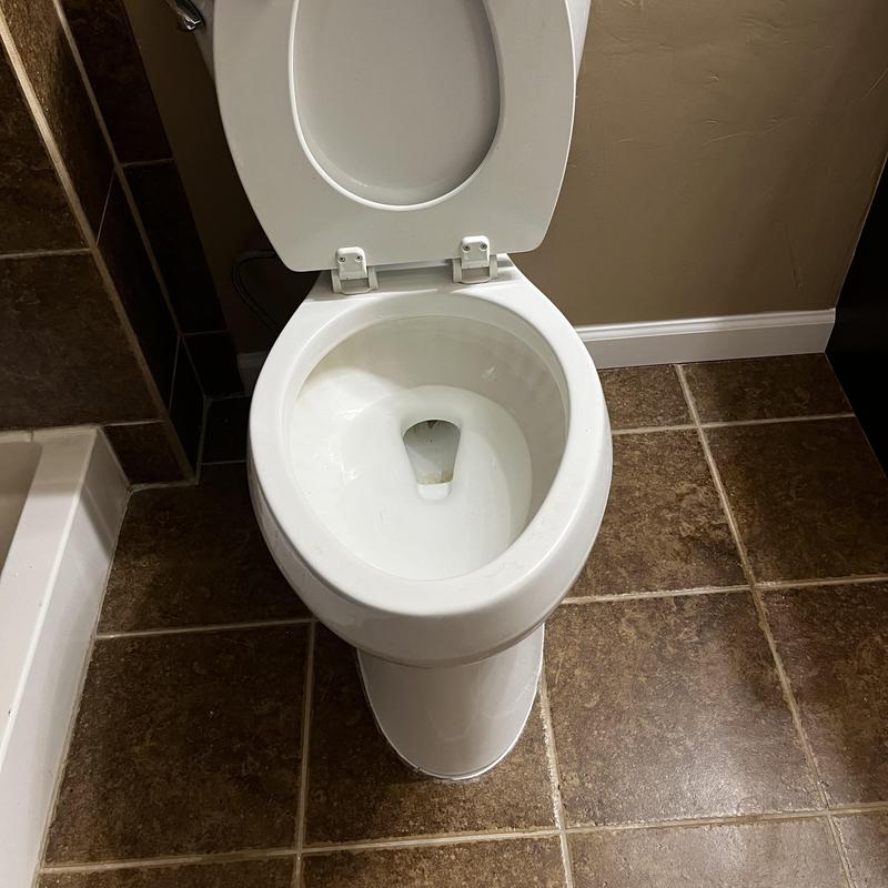 Toilet bowl with flange and caulking on tile floor