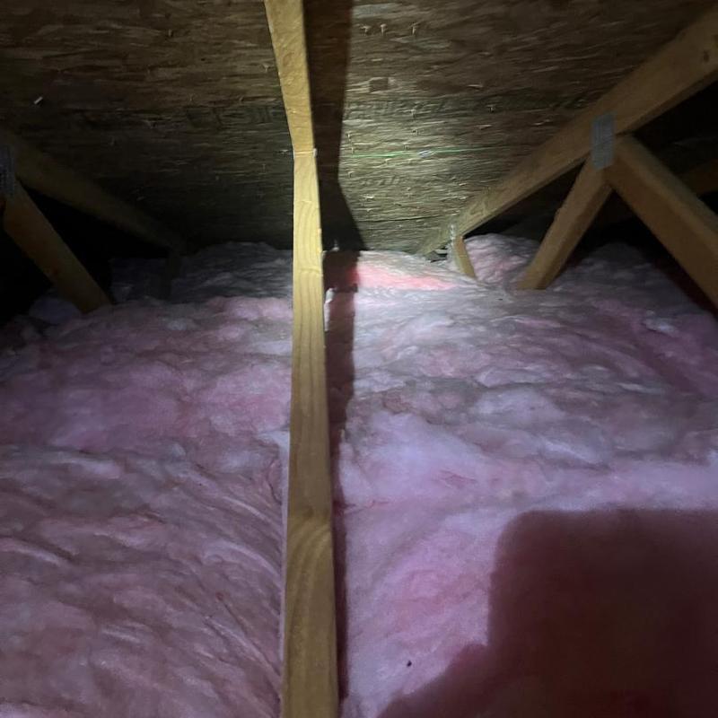 Attic roof insulation with visible wood framing beams