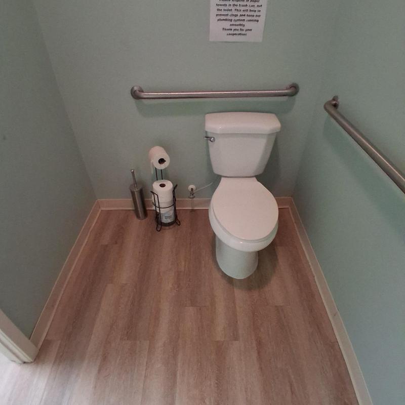 Toilet with grab bars and vinyl flooring in bathroom