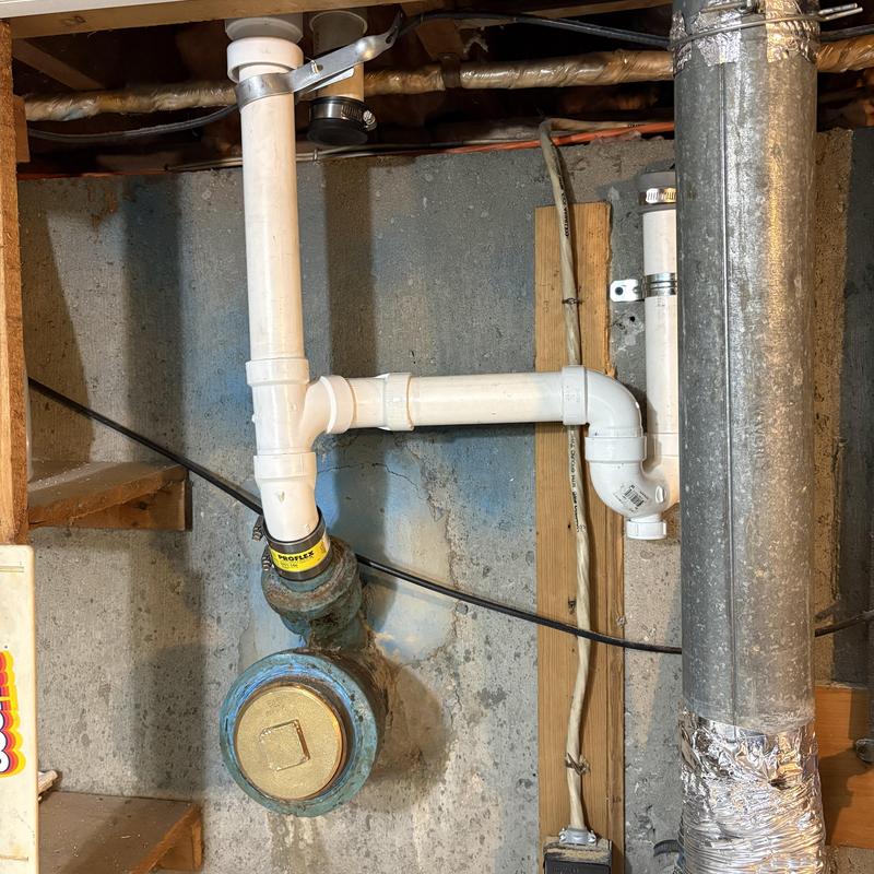 White PVC drain pipes rerouted in basement stack system