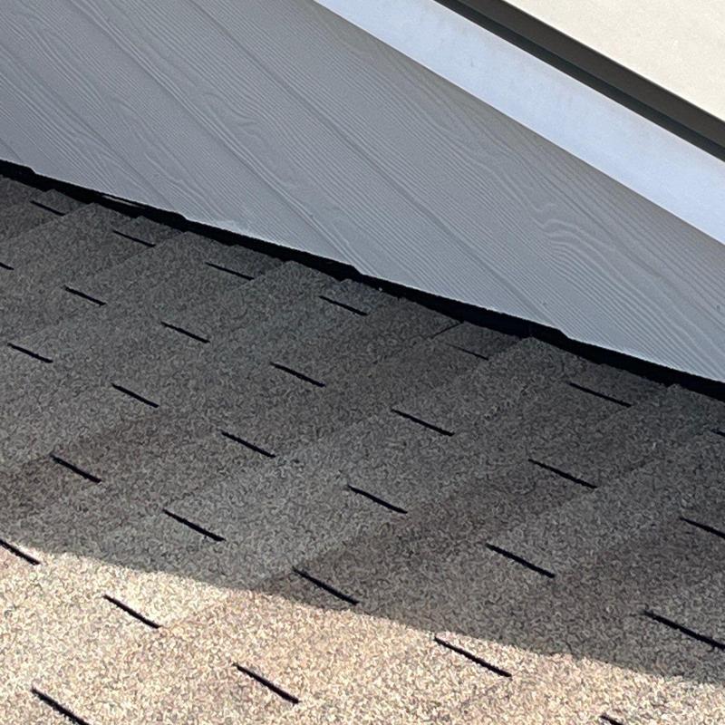 Roof shingles with hail damage near siding and flashing