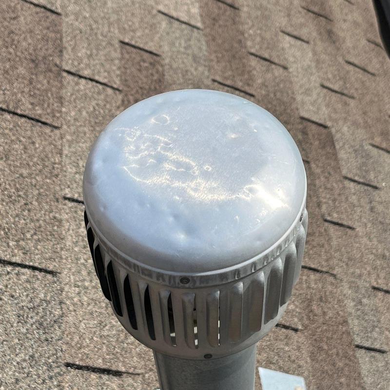 Roof vent cap with hail dents on shingle roof