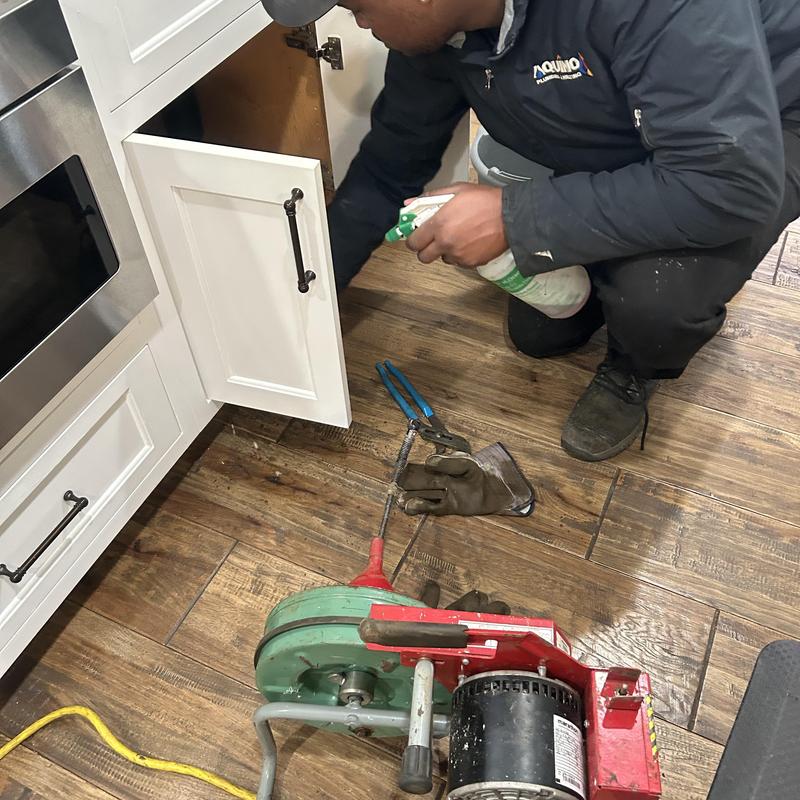 Kitchen drain snake machine with plumber using spray bottle