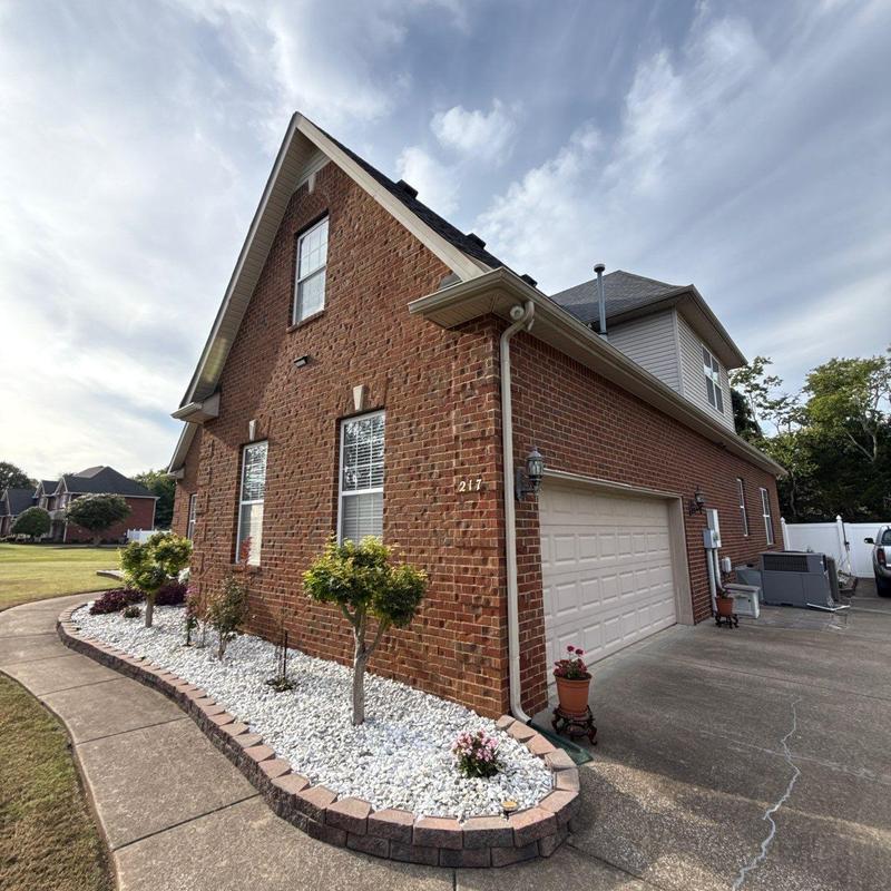 Brick exterior with landscaping and driveway curb