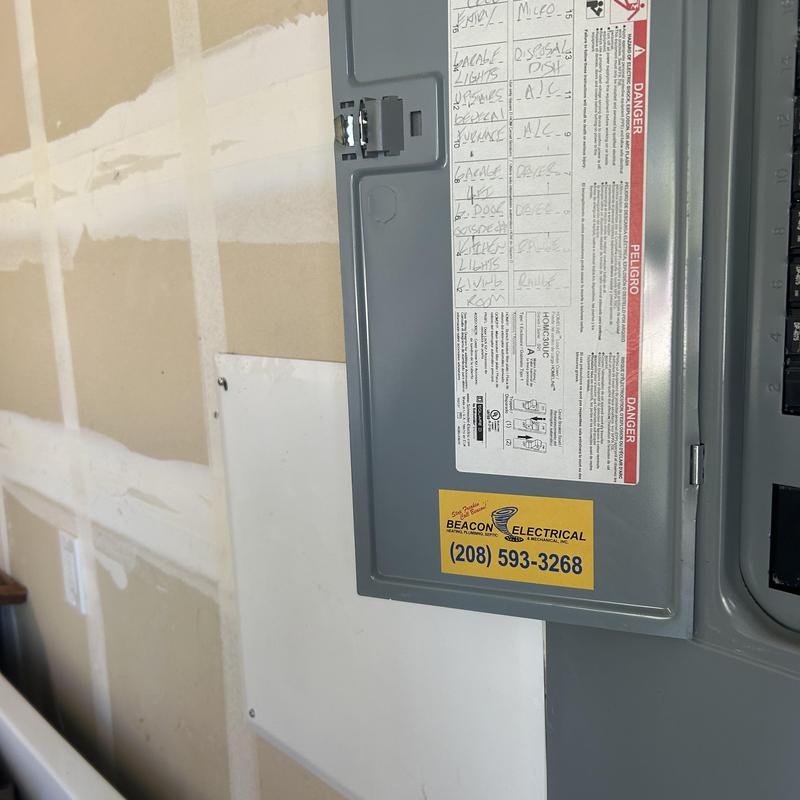 Electrical panel with labeled circuit breakers and warnings
