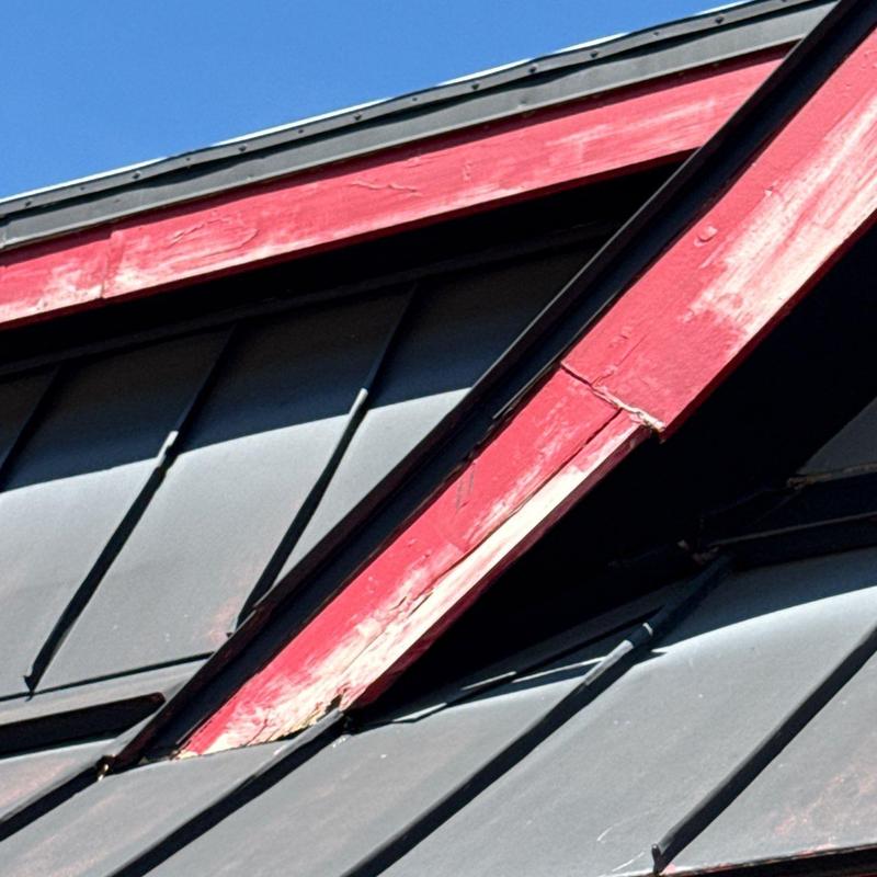 Metal roof panels with damaged red trim
