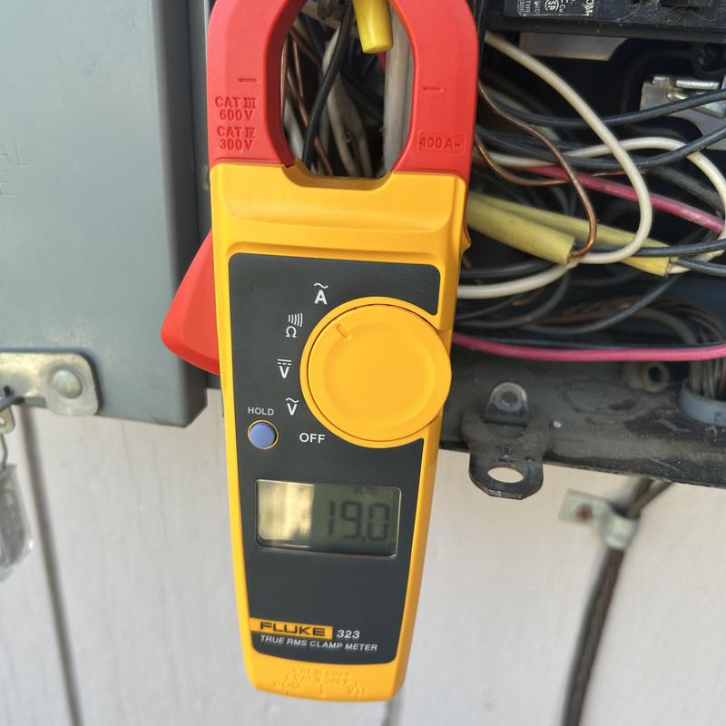 Clamp meter measuring amperage on water heater panel wiring
