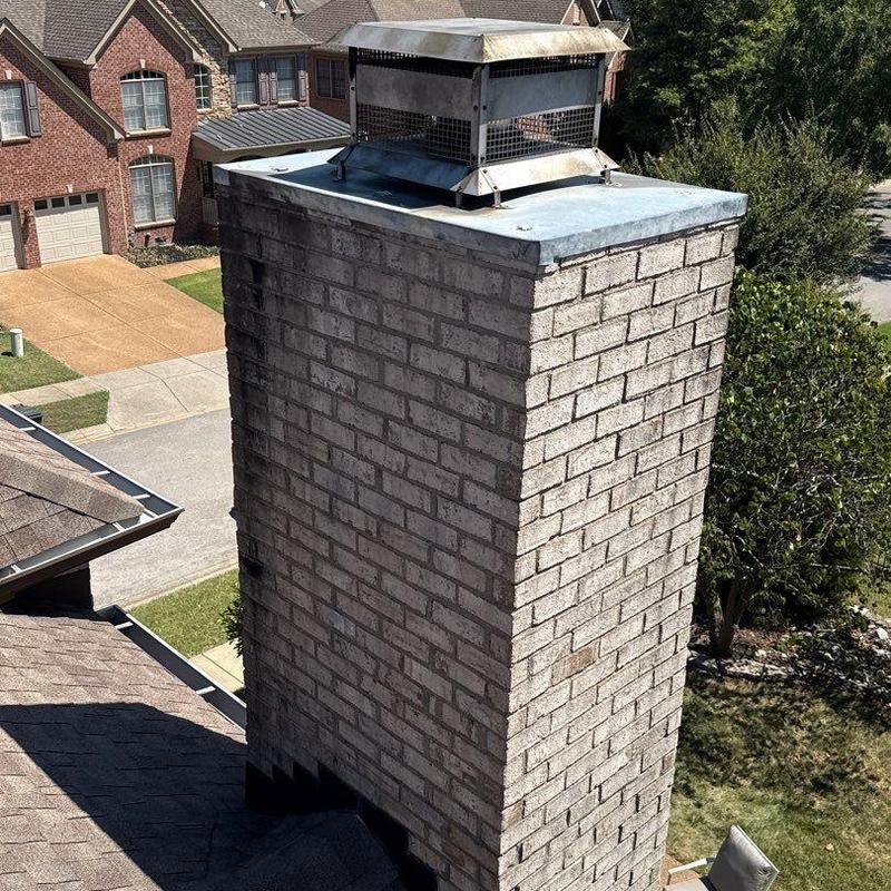 Brick chimney with metal chimney cap on residential roof