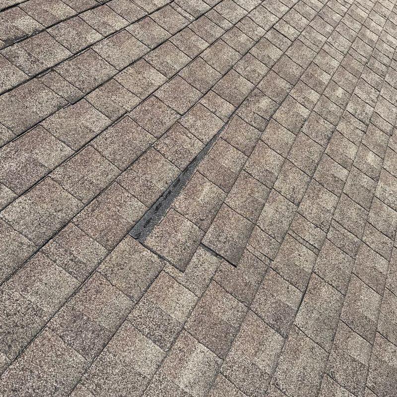 Hail-damaged asphalt roof shingles close-up view