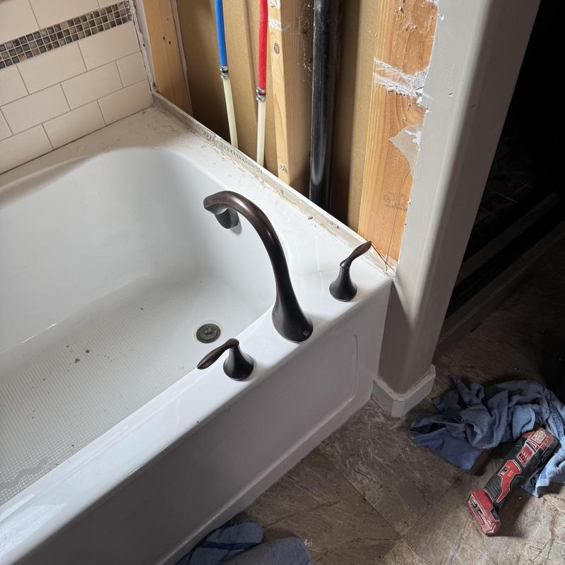 Tub faucet installation with exposed plumbing in bathroom