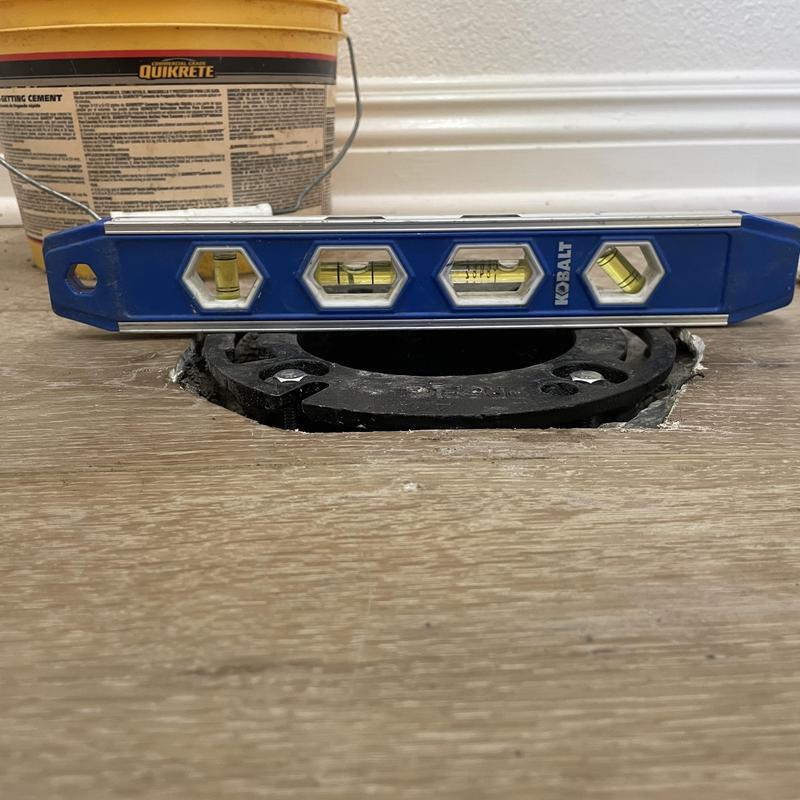 Toilet closet flange with level on hardwood floor