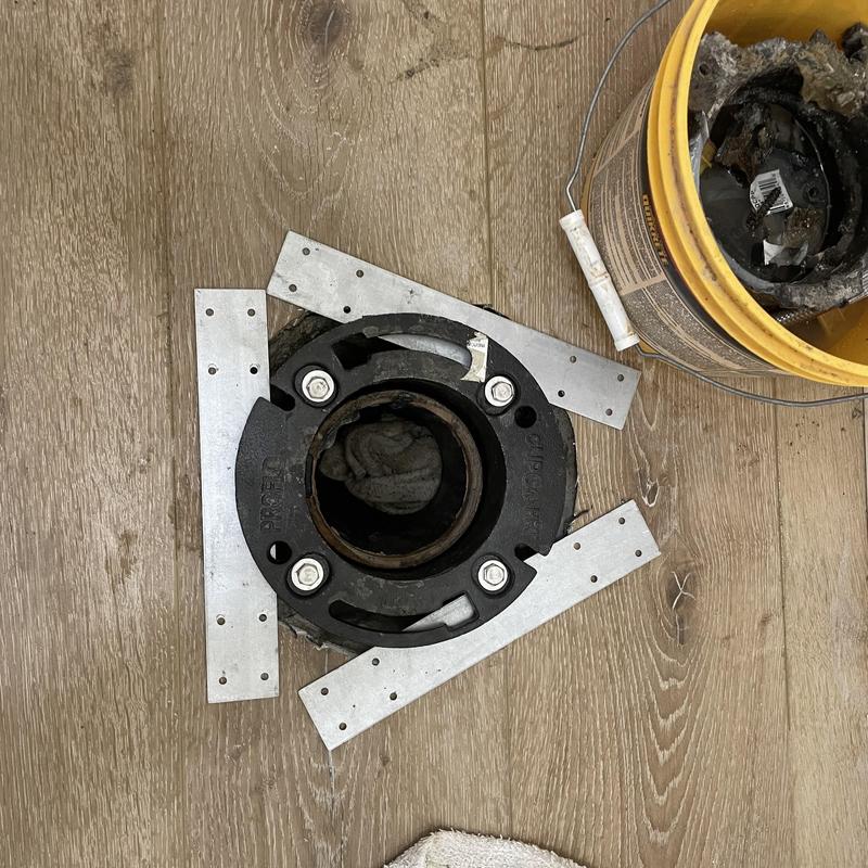 Cast-iron toilet flange installation with braces on wood floor