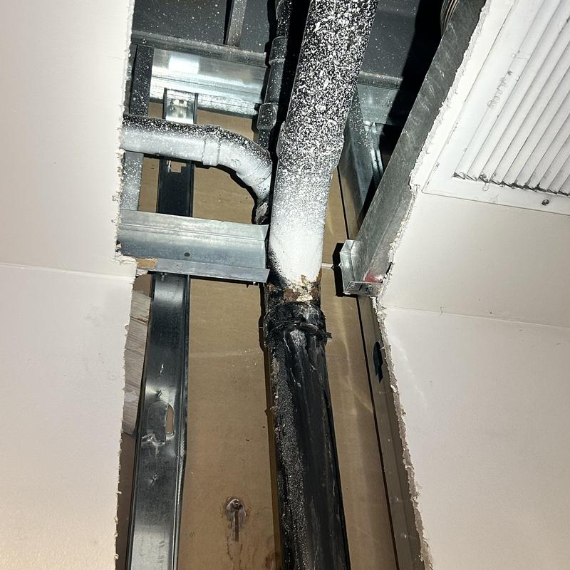 Drain line pipe with cut drywall and ceiling damage