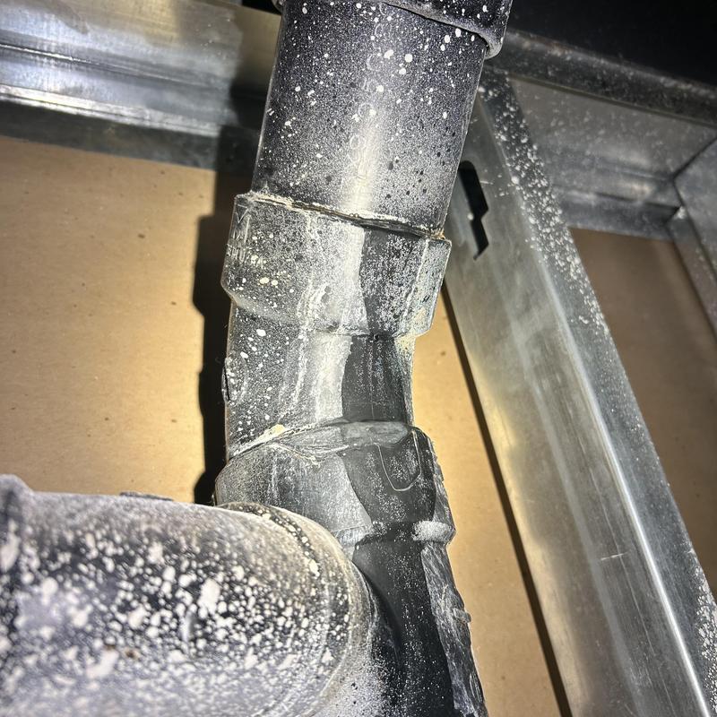 Drain line PVC pipe with no-hub coupling in ceiling wall