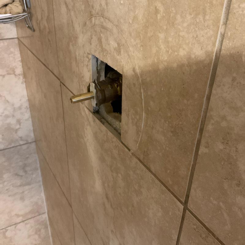 Shower valve stem exposed in tiled wall cavity