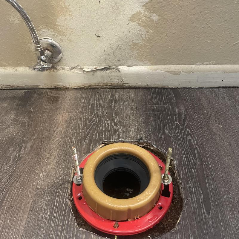 Toilet flange installation on dark wood flooring