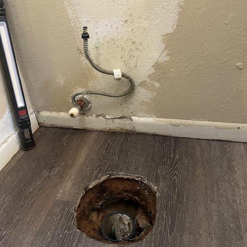 Toilet flange and plumbing pipe exposed in floor cutout