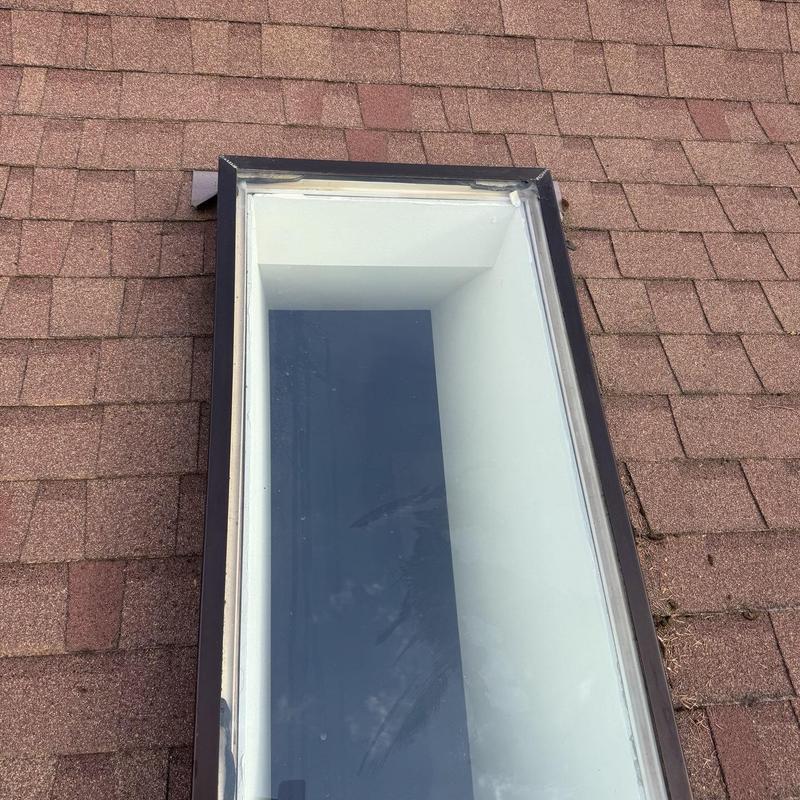 Skylight on shingle roof after cleaning and moss treatment