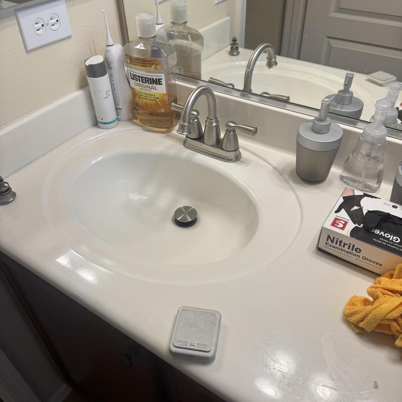 Bathroom sink faucet and countertop with cleaning items