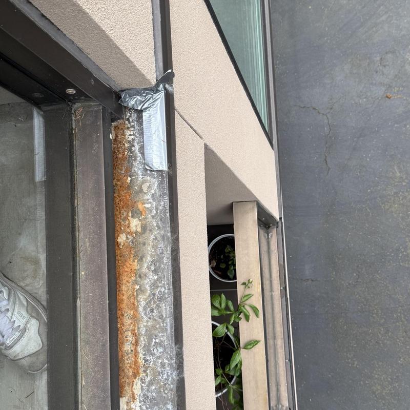 Metal window frame with rust and taped patch detail
