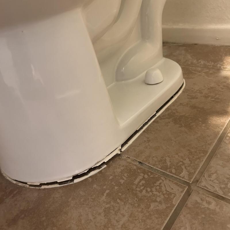 Toilet base with cracked caulking on tile floor