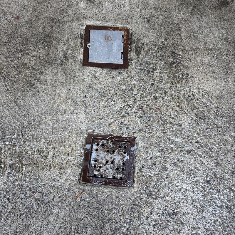 Driveway floor drain with metal grates on concrete surface