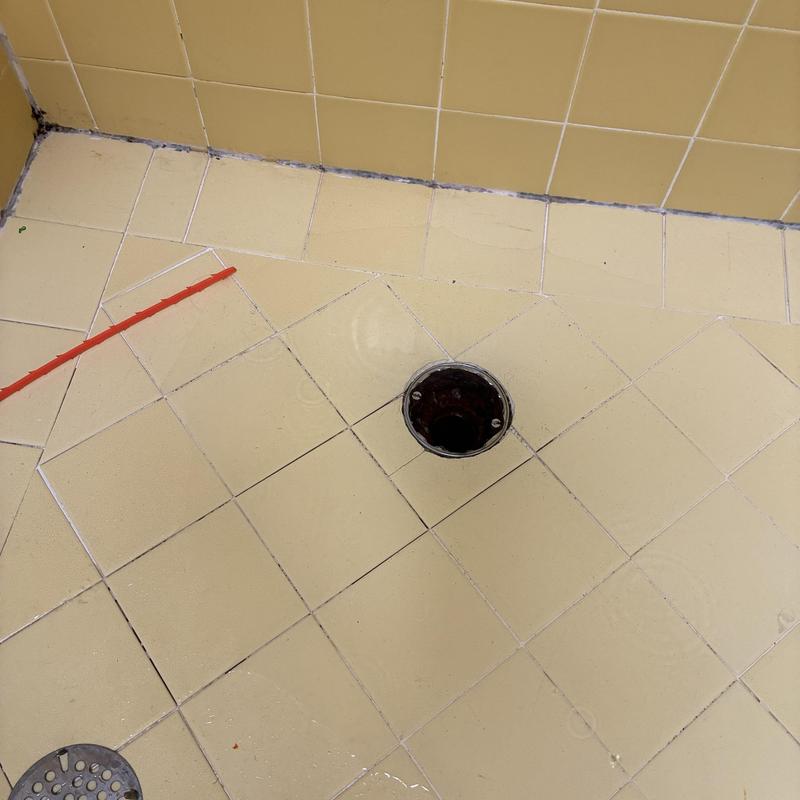 Shower drain opening with plumbing tool nearby